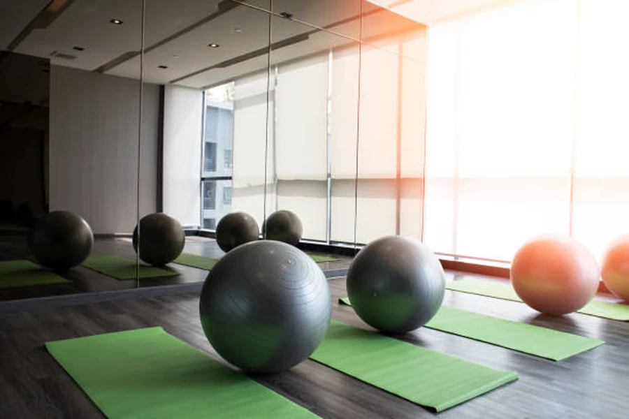 Tapetes de ioga e bolas em frente aos espelhos do ginásio