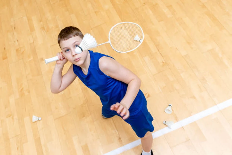 Young boy lining up shuttlecock with badminton racket on court