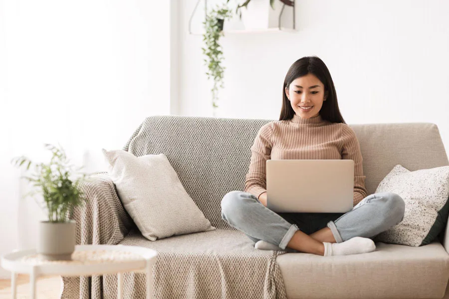 Young lady sitting on a couch and using a laptop to search