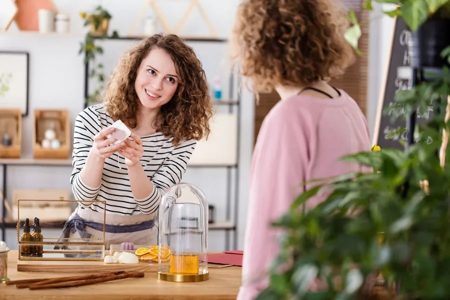 Young seller showing an organic skin product to a customer