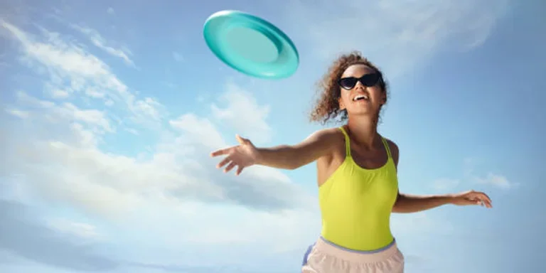 Young woman throwing a light blue frisbee in the air