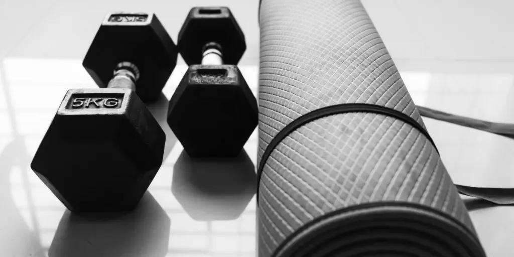 A dumbbell set and an exercise mat on the floor