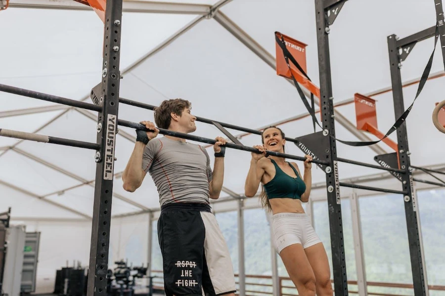 A man and woman using a pull-up bar station