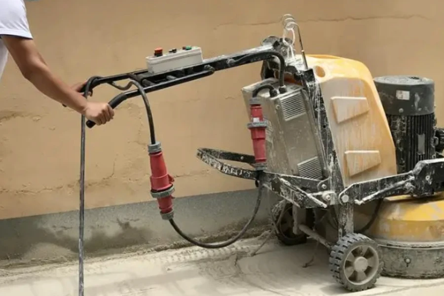 Seorang pria menggunakan penggiling lantai pada beton