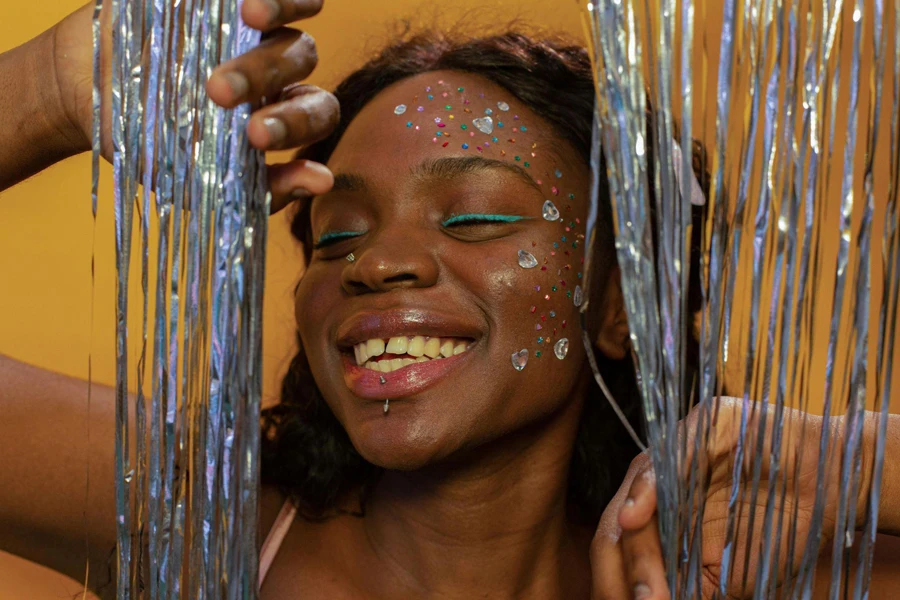 a smiling woman with rhinestone stickers on her face