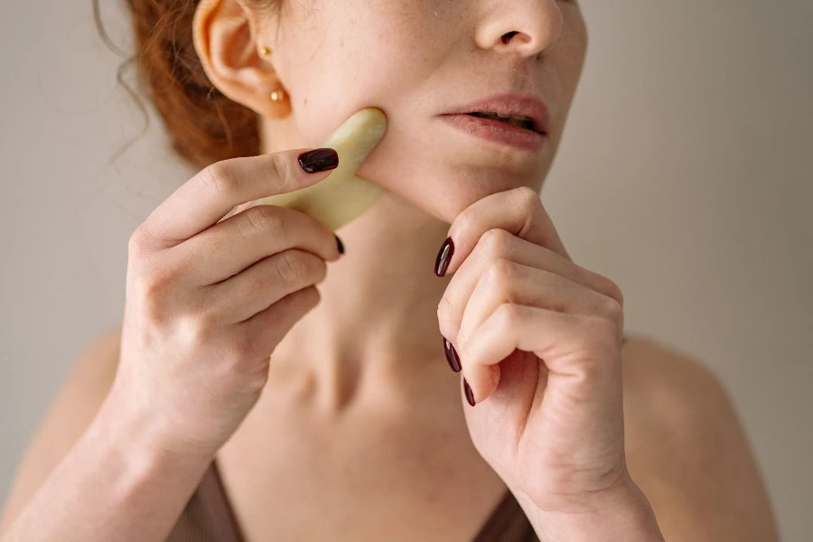 A woman using a gua sha on her jawline