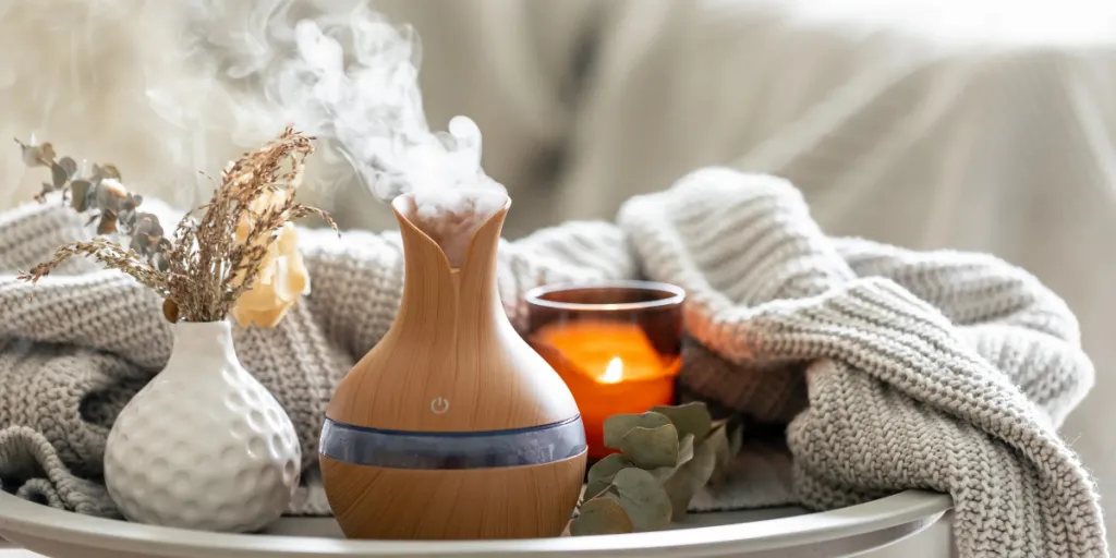 Aroma composition with a modern aroma oil diffuser, candles and a knitted element in interior of room