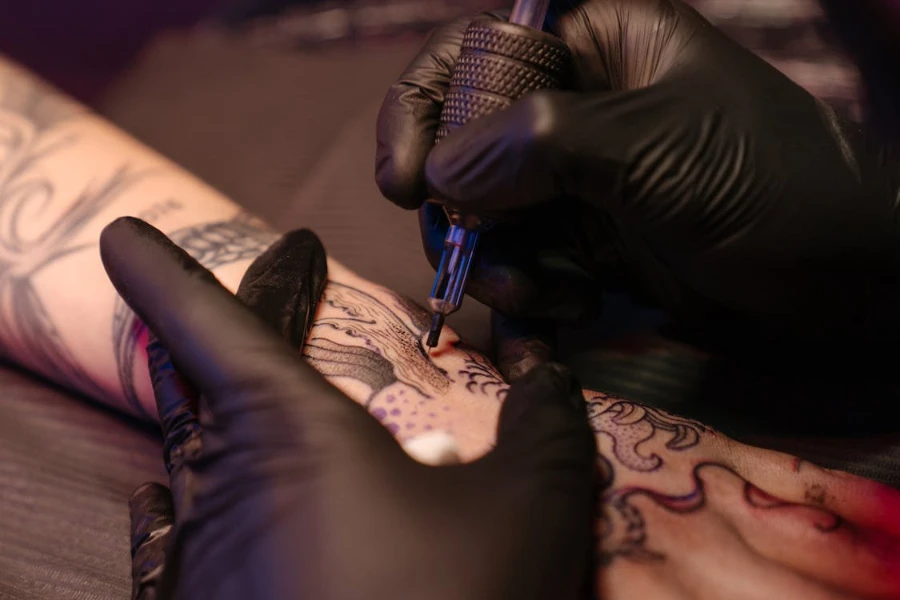 Artis menggunakan mesin tato dengan pegangan hitam