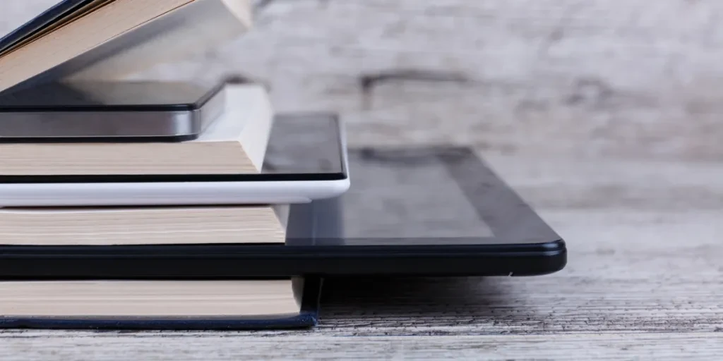 E-reader and tablets among a stack of books