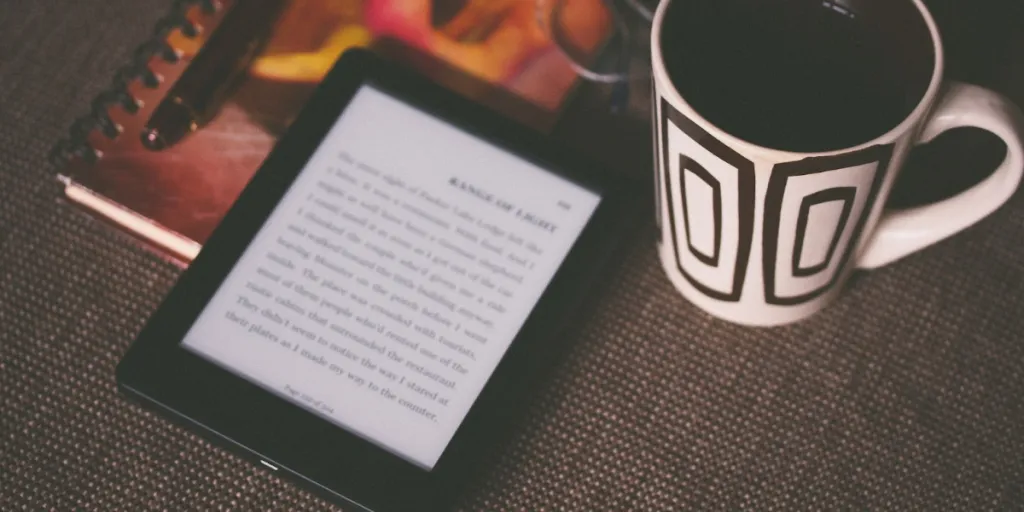 E-reader on a table beside a cup of coffee