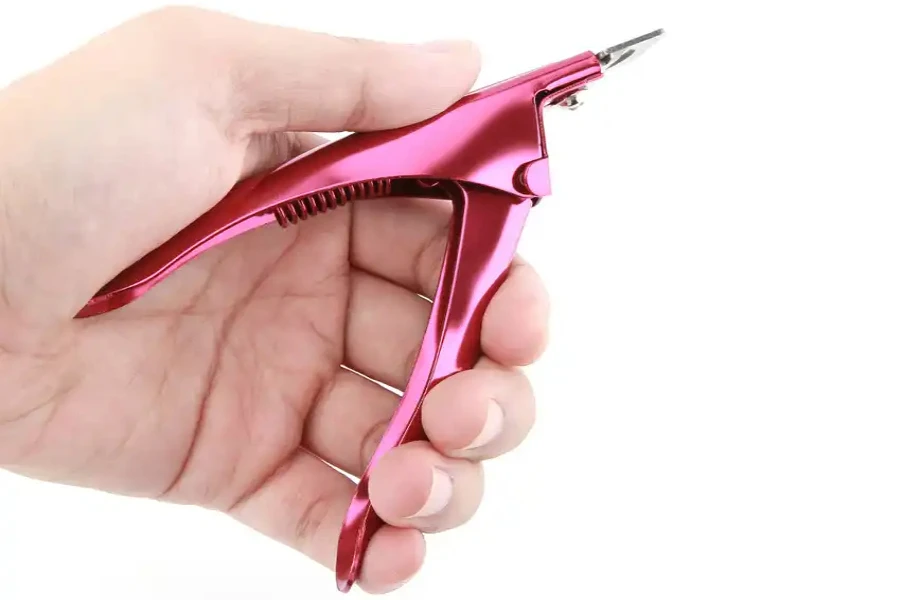 Hand holding a purple guillotine nail clipper