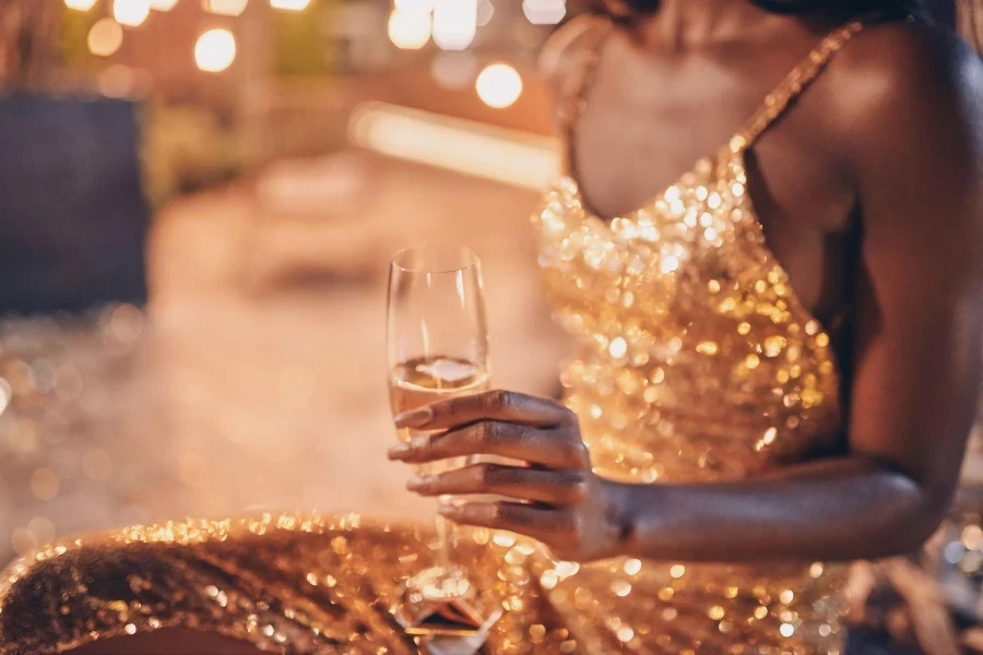 beautiful young African woman in evening gown holding flute with champagne