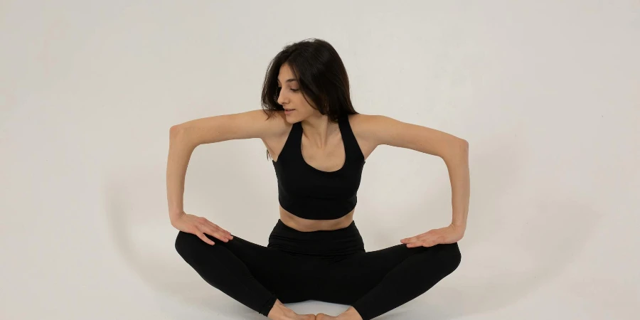 Fit woman sitting in butterfly pose and pressing on legs