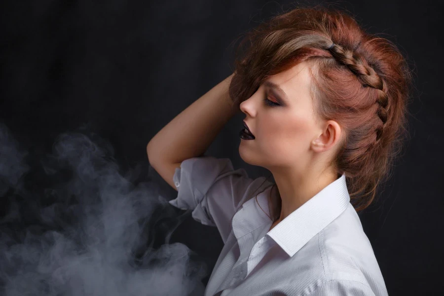 Young and beautiful girl with dark make-up on a dark background with smoke