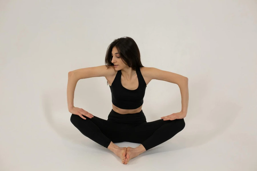 Fit woman sitting in butterfly pose and pressing on legs