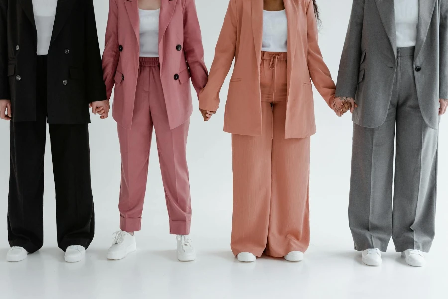People Wearing Blazers and Pants Holding Hands while Standing Together