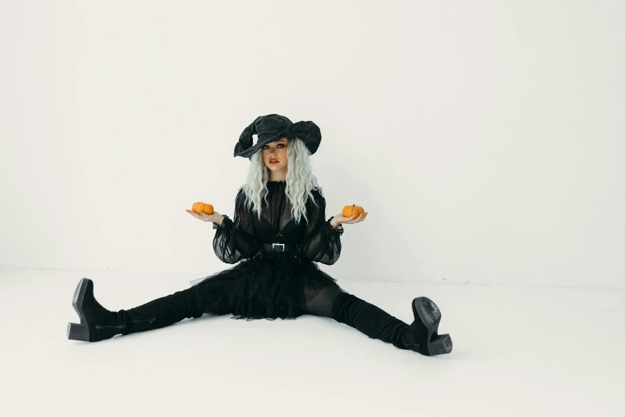 Woman in Black Holding Two Pumpkins