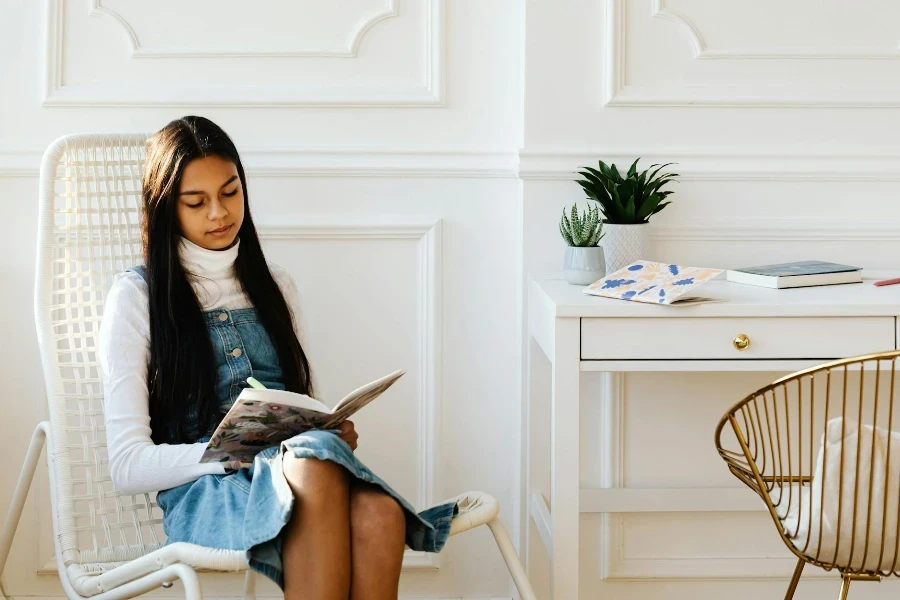 Young Woman Sitting on White Rattan Chair Writing on a Notebook