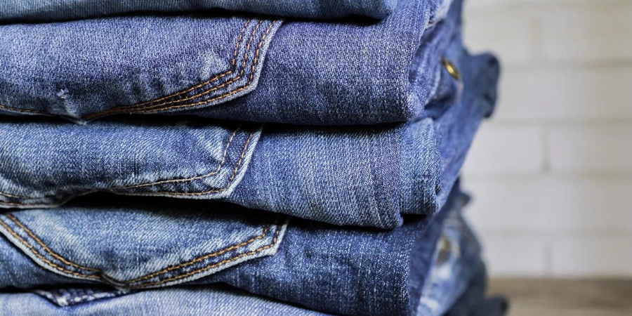 Stack of blue jeans on wooden shelf
