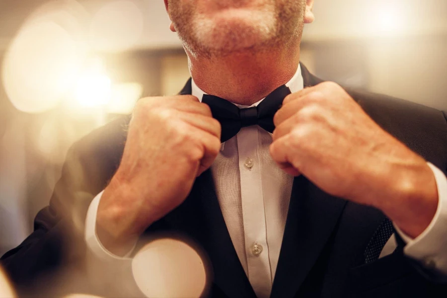 Hands, fix bowtie and tuxedo for party