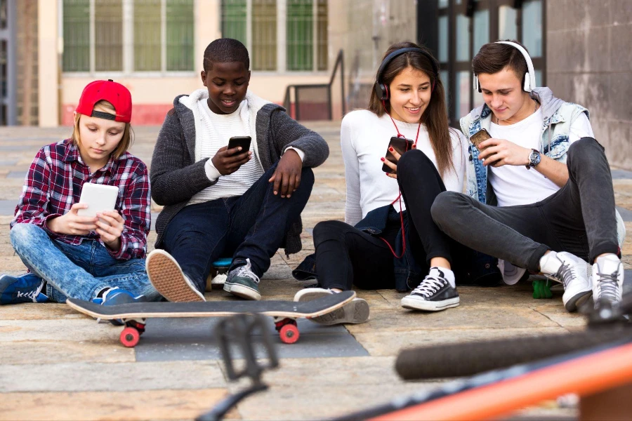 Attractive teens playing on smart phones and listening to music