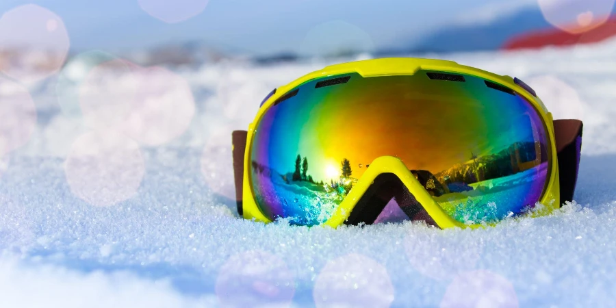 Vista da máscara de esqui amarela na neve gelada branca com reflexo das montanhas