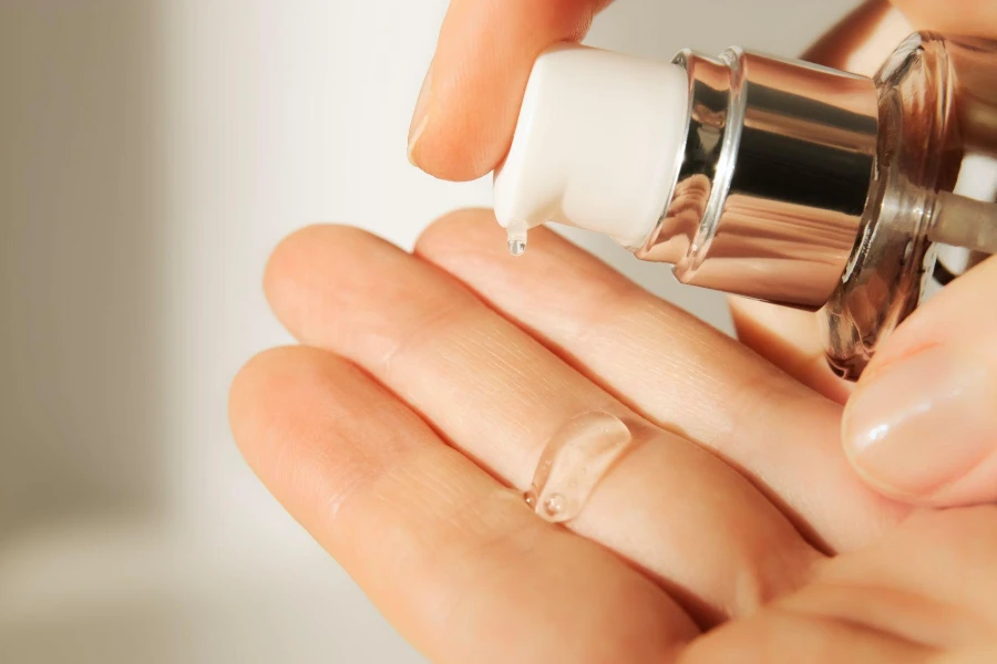 Ahli kosmetologi menuangkan asam serum hialuronat pelembab pembersih bening