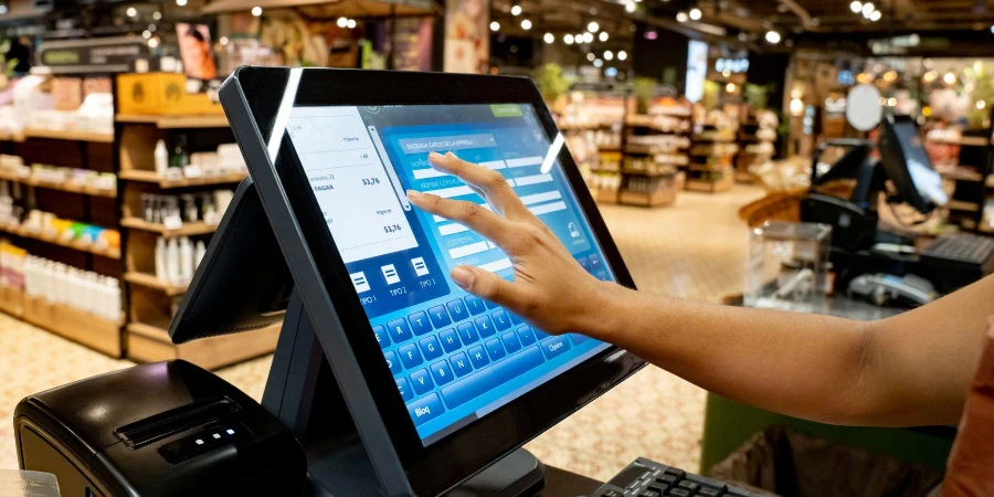 Close-up on a cashier registering products at the supermarket using a touch screen