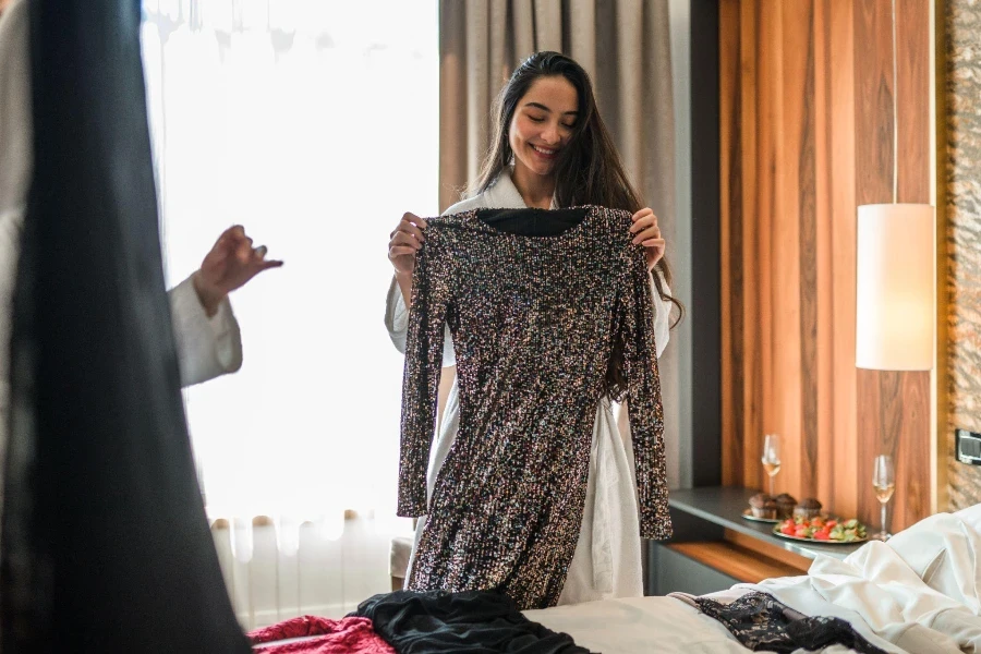 Happy young woman trying out clothes before going out with her girlfriends.