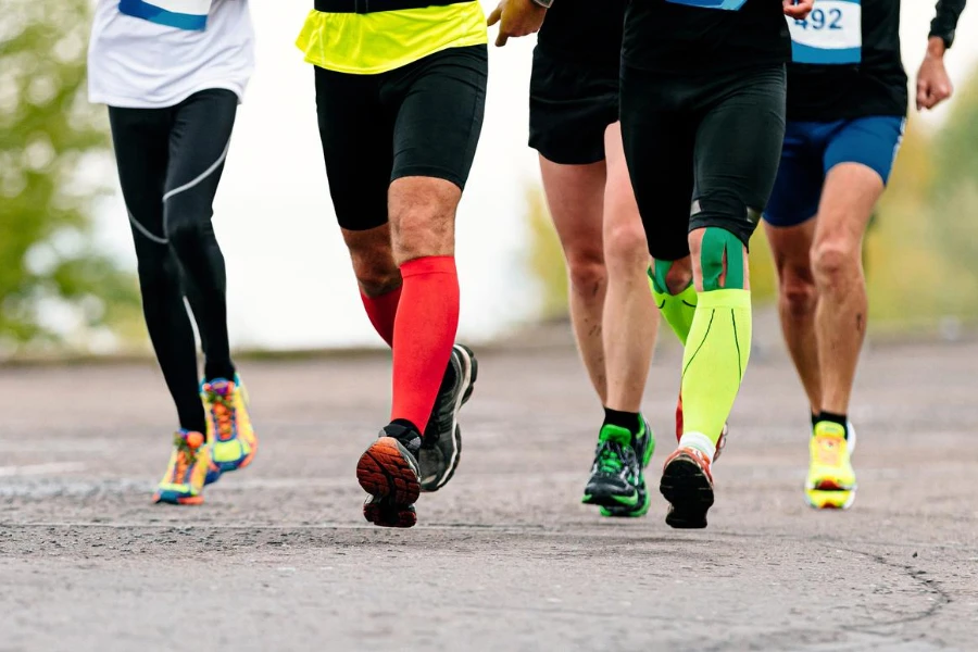 pernas corredores masculinos em meias de compressão e fita kinesio correm maratona