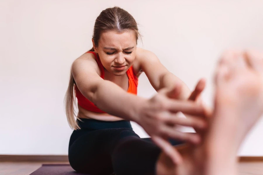 Une jeune femme qui étire une jambe ressent une douleur à la jambe