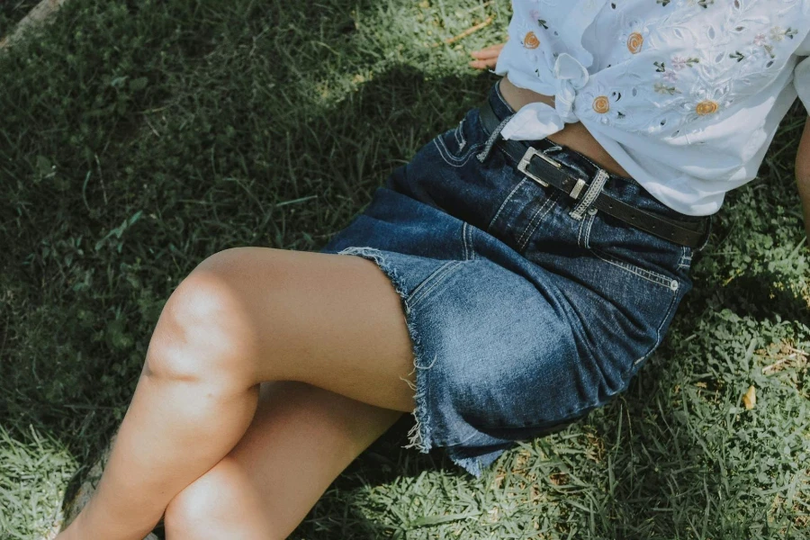 Woman in White Shirt and Blue Denim Skirt Sitting on Green Grass