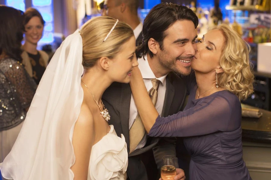 Mother kissing groom at wedding reception