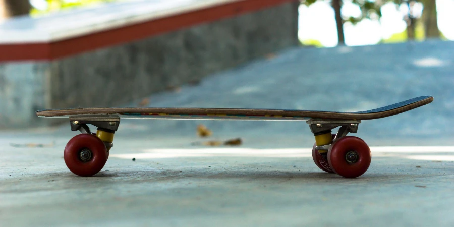 Side view of penny board with red wheels stands on the ground in a skatepark