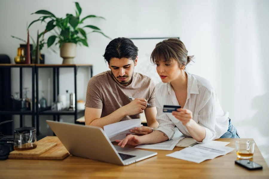 Boyfriend looking at bills while his girlfriend holding credit card