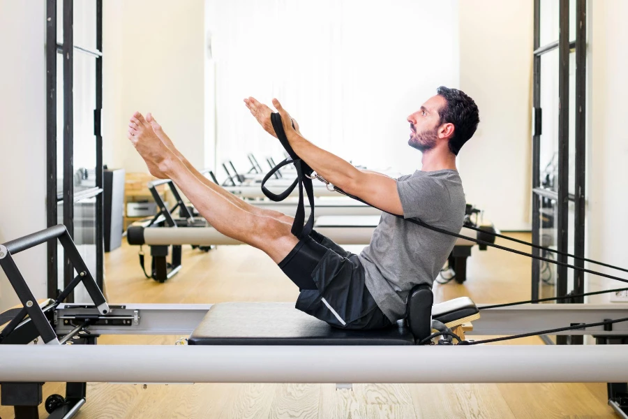 Fit muscular man doing a teaser Pilates exercise