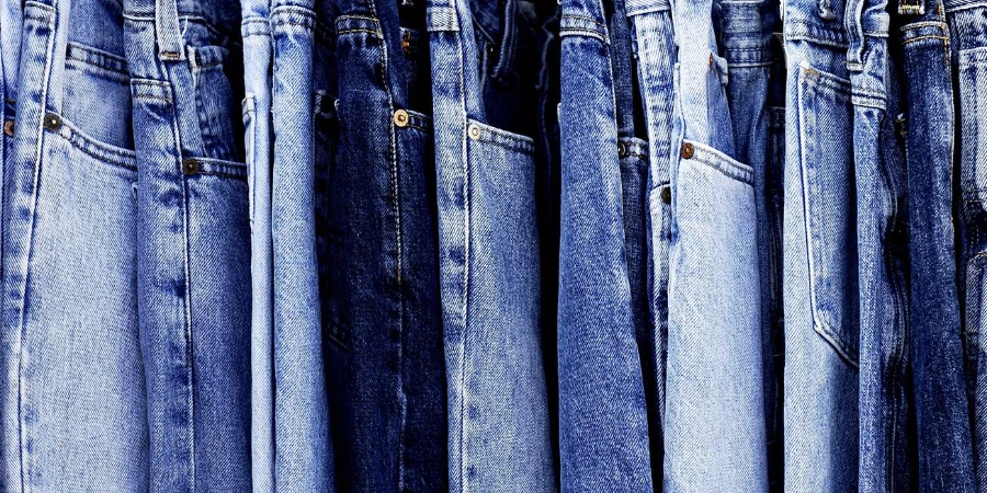 A rack of a variety of blue denim jeans in various shades of blue