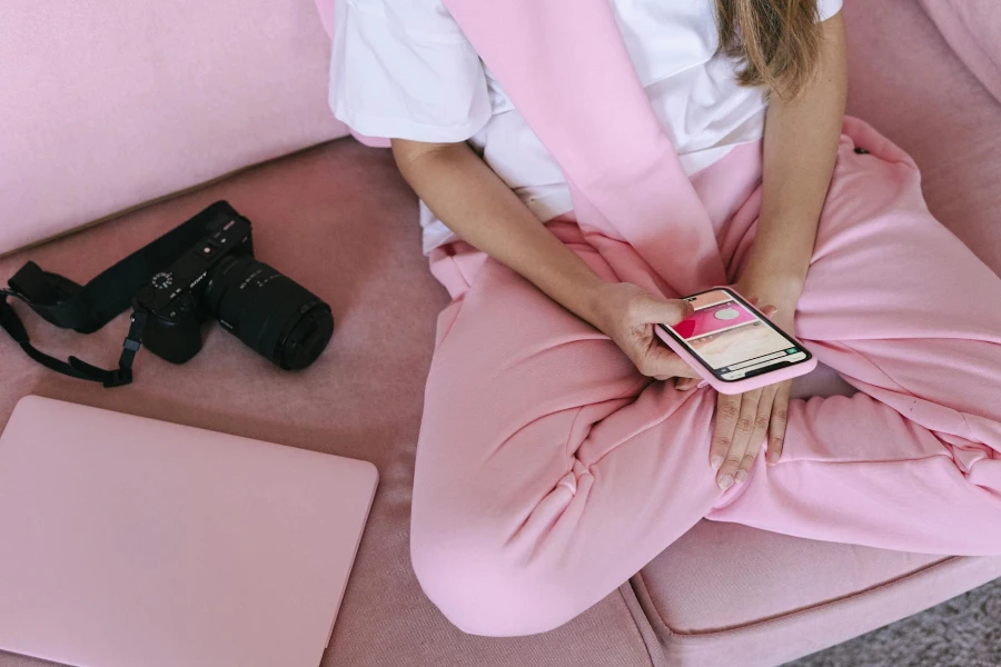 A Person in Pink Pants Sitting on the Couch while Holding a Mobile Phone