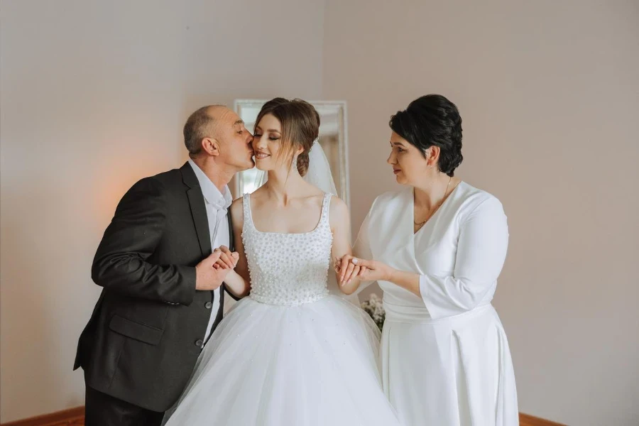 Happy parents hold the hands of the bride who is getting married and support her