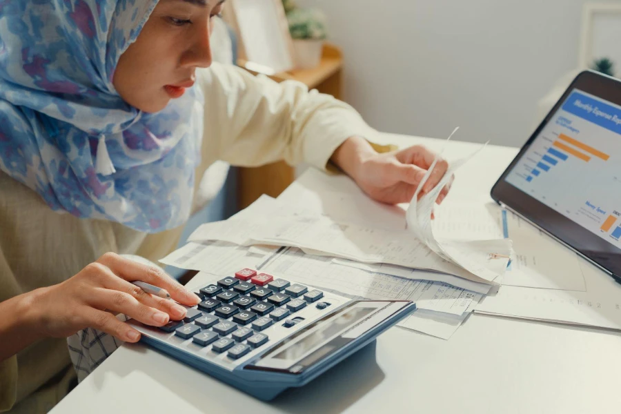Young Asian woman with hijab using tablet calculator