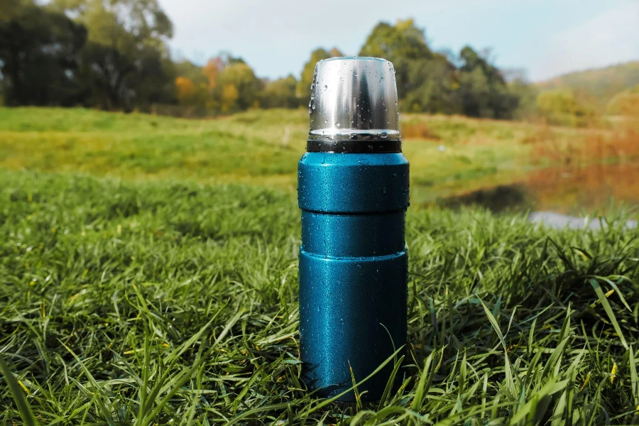 Steel vacuum thermos on a forest background.