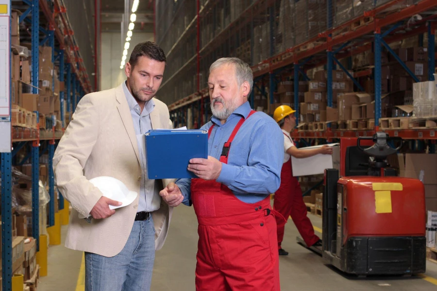 Manager and older worker browsing papers in warehouse