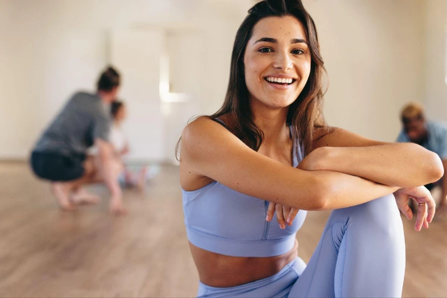 Retrato de una joven en forma sonriendo a la cámara mientras está sentada en un estudio de Pilates