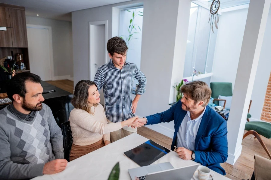 Family and advisor shaking hands at house