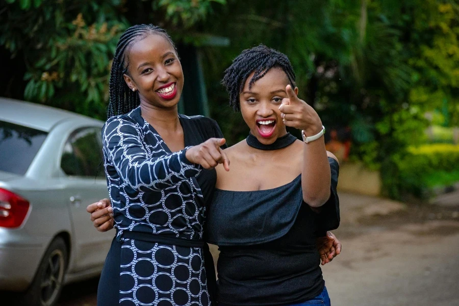 Two Women Smiling While Standing Near Vehicle Outdoors