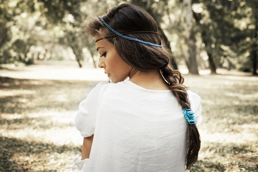 young beautiful woman portrait in white dress and blue beads in hair