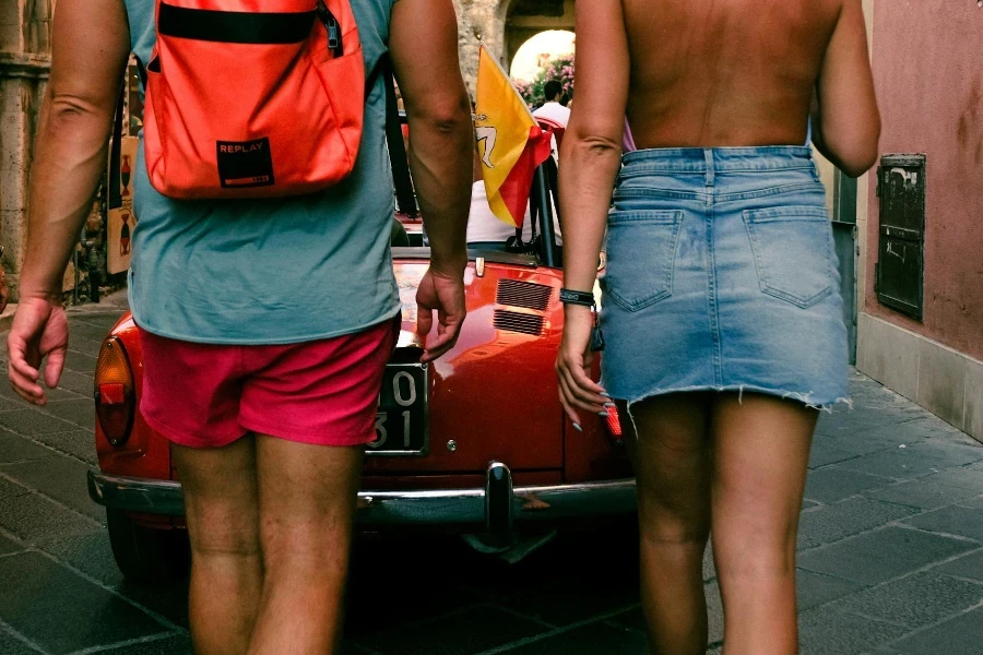 Back View of Woman in Denim Skirt and Man With Backpack Walking