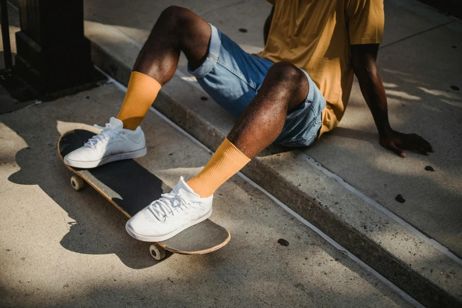 Crop anonymous African American male skater in t shirt and denim shorts