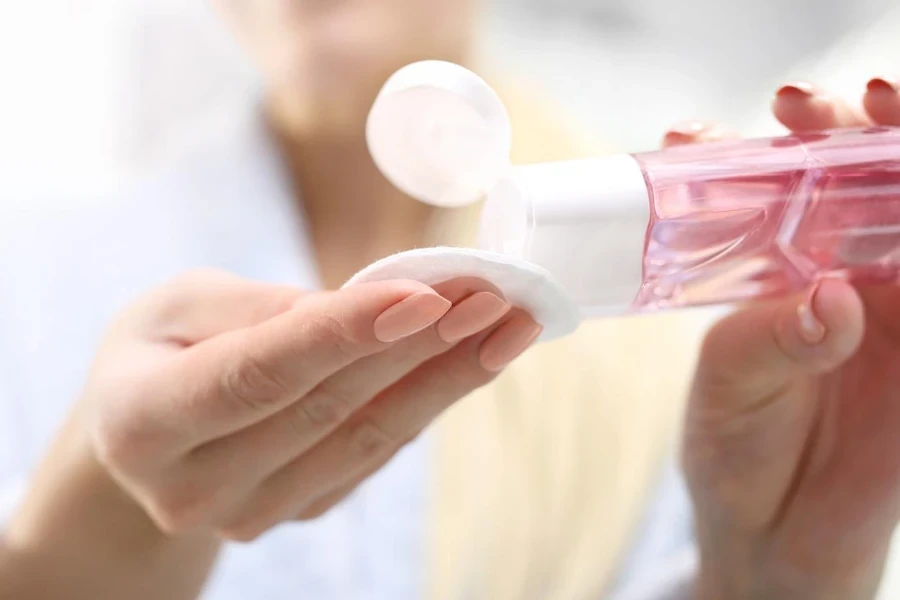 Woman pours makeup remover on a cotton pad