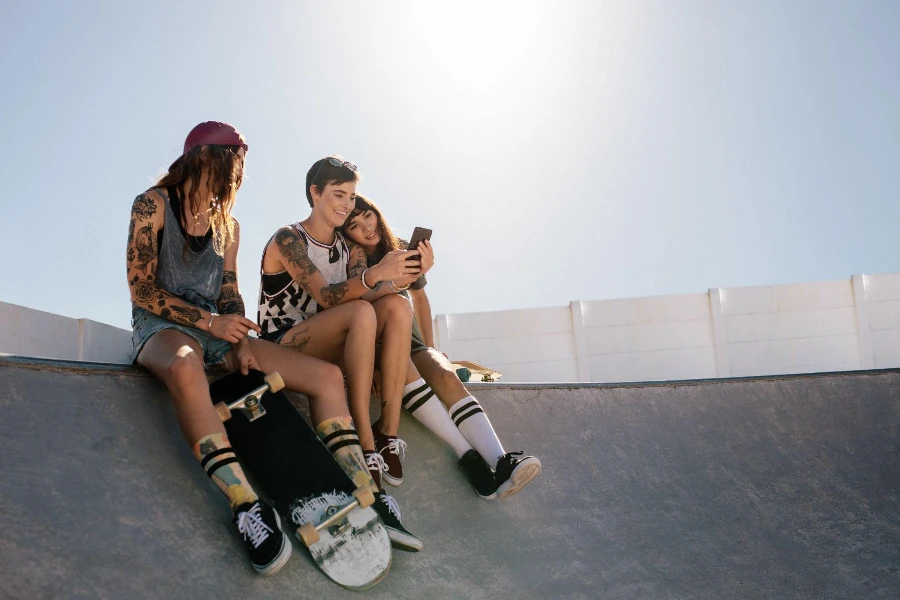 Three women skaters using smart phone together at skate park